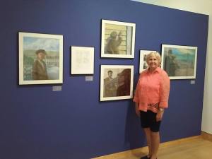 Helen Foster James (co-author with Virginia Loh Hagan) next to oil paintings and sketches from their book 